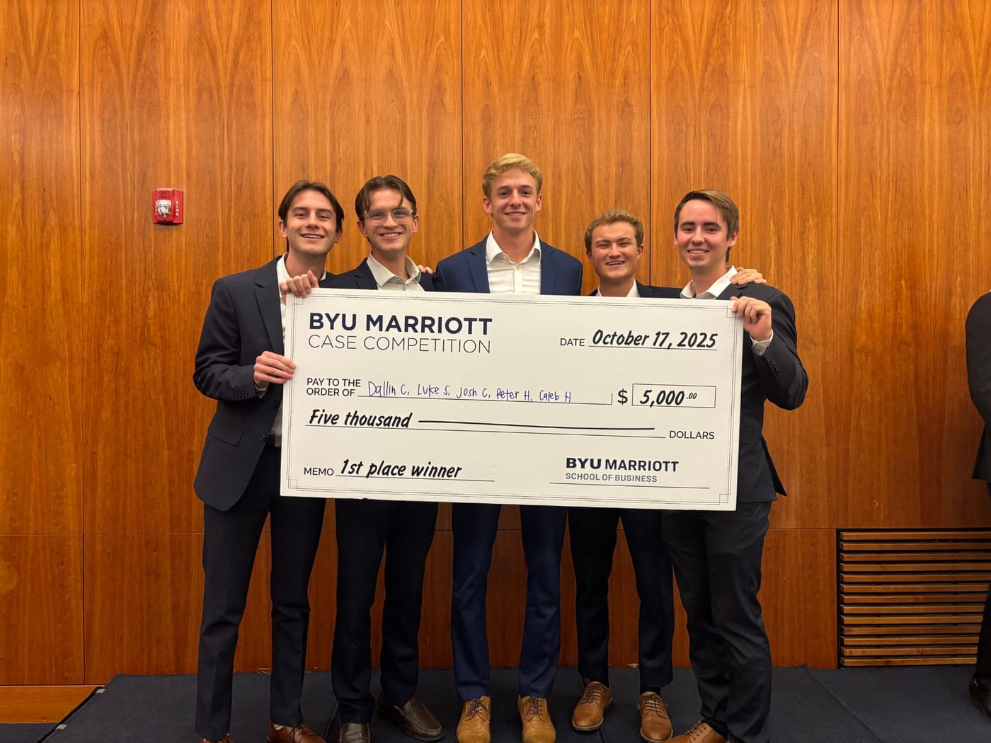 Caleb and his four teammates holding the $5,000 first-place check from the BYU Marriott Case Competition, October 17, 2025